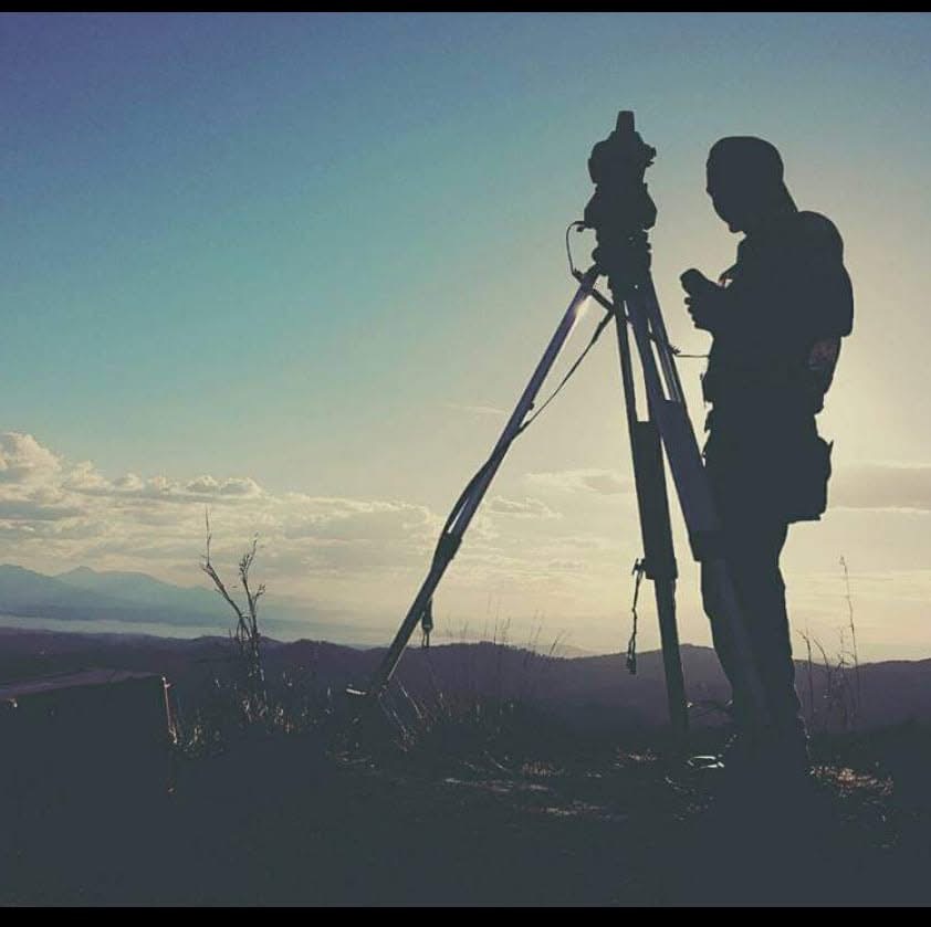 Topógrafo realizando un levantamiento con estación total al atardecer